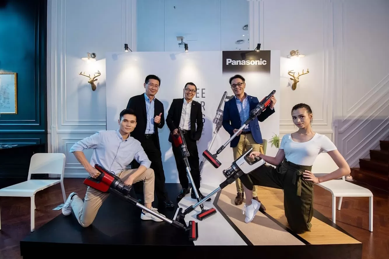 A group of people posing with the cordless vacuum cleaners, with 3 senior Panasonic Malaysia officials at the back and 2 dancers (male & female) in front.